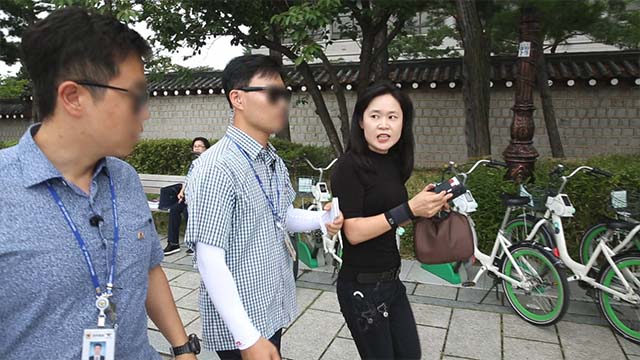 Un’irritata O Myung-ok viene fermata dalle guardie di sicurezza mentre tenta di lanciarsi verso i manifestanti durante la conferenza stampa
